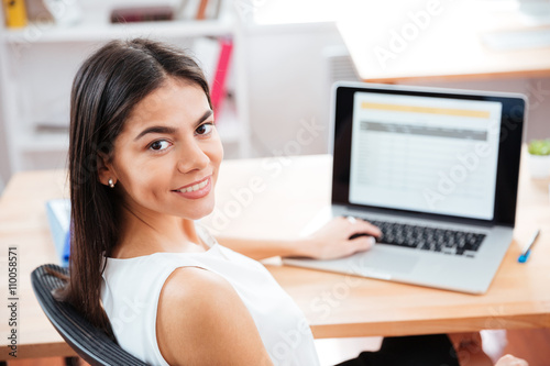Businesswoman sitting at the table with laptop in office