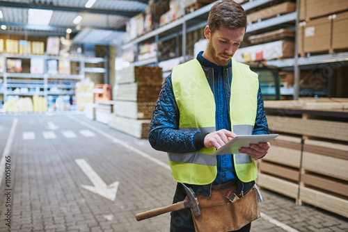 Fotografie Young warehouse worker consulting a tablet