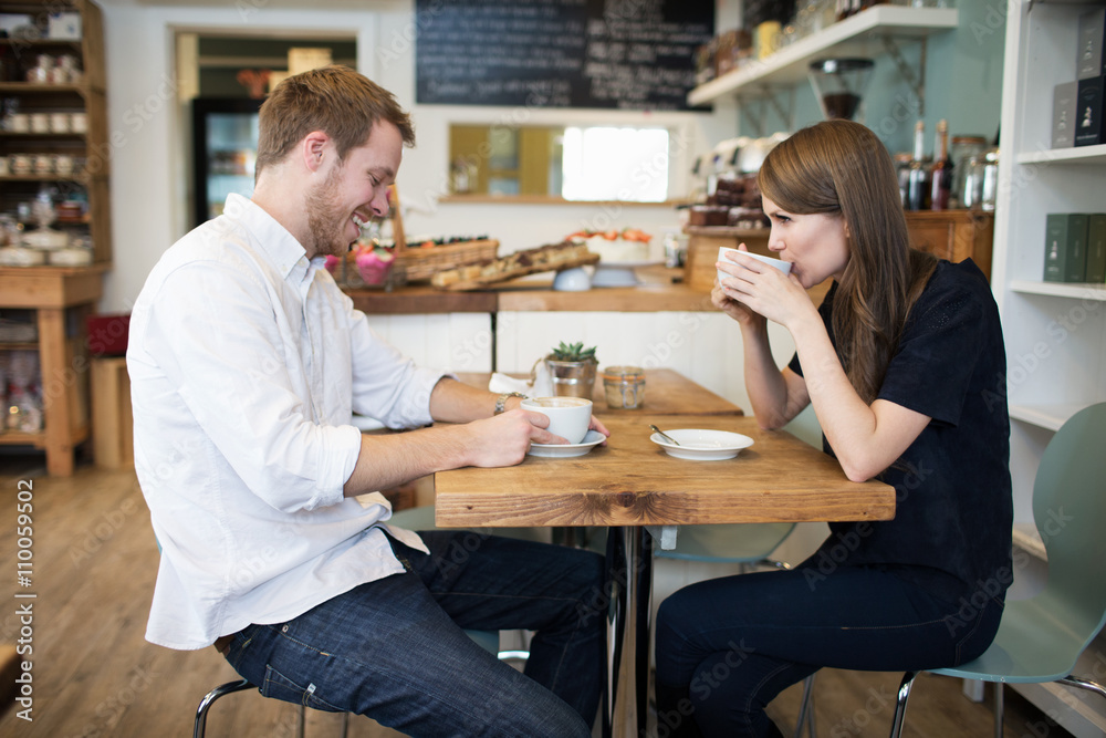  Young Couple Sitting At Table In Coffee Shop Together	