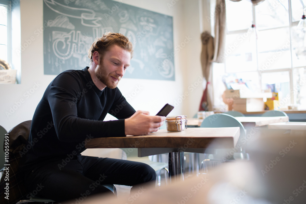 Young Man Checking Mobile Phone In Coffee Shop Young Man Checking Mobile Phone In Coffee Shop