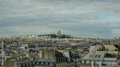 Timelapse shot of Paris panorama with clouds moving and sun rays walking over the city reaching the Sacre Coeur Basilica in the distance photo