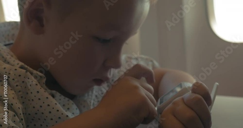 Little boy is using smart watch on his hand during the flight in the plane. photo