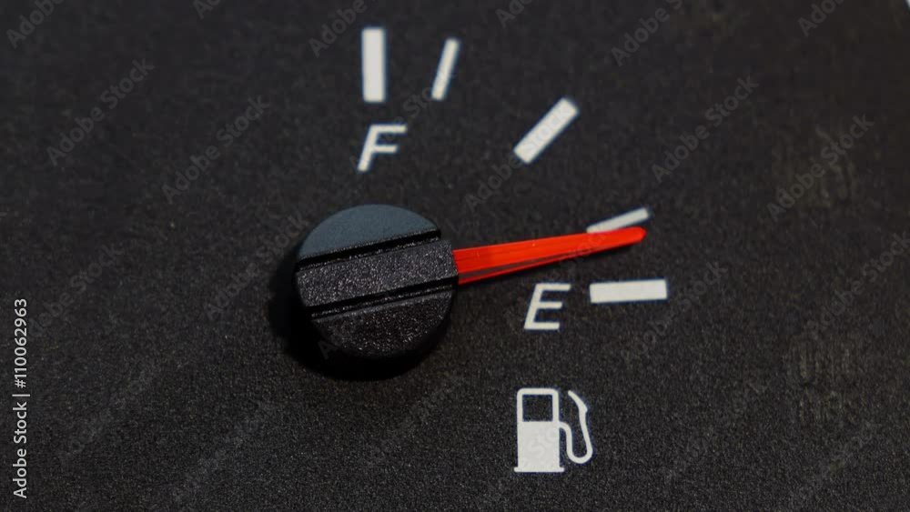 Close up shot of real dashboard and car fuel gauge quickly drops from full to empty. Not animation
