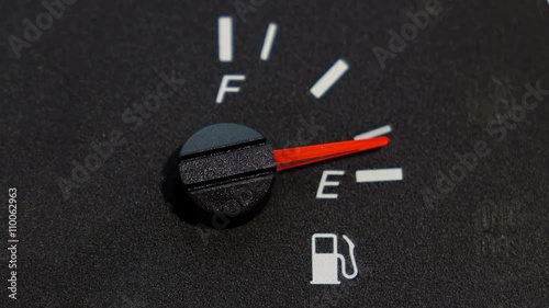 Close up shot of real dashboard and car fuel gauge quickly drops from full to empty. Not animation
