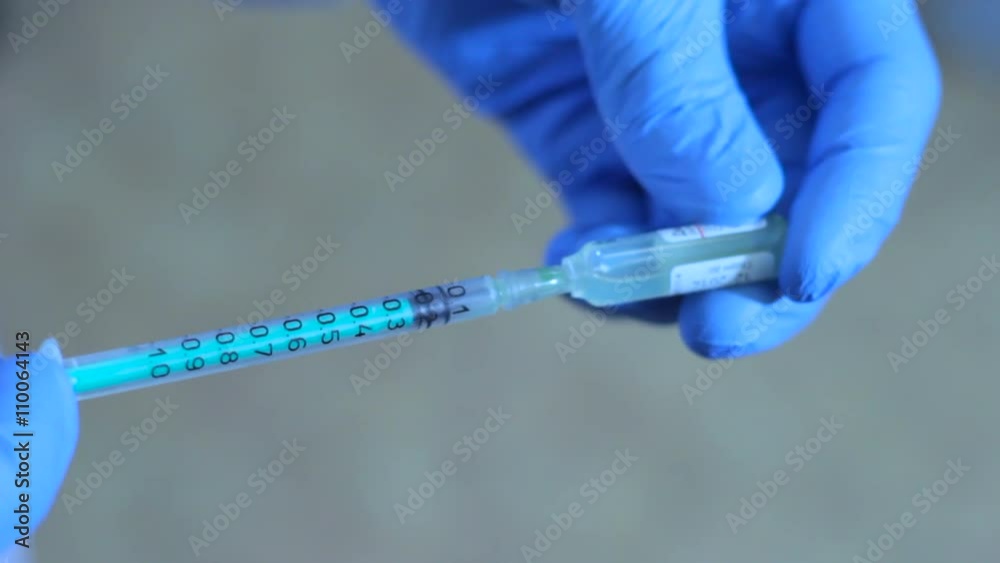 doctor gaining medication from the vial into the syringe doctor gaining medication from the vial into the syringe
