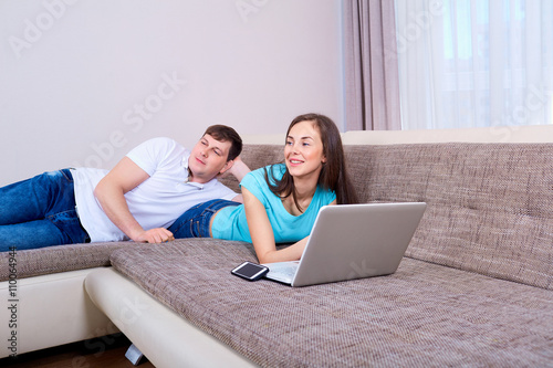 Happy wife and husband on the couch with a laptop.