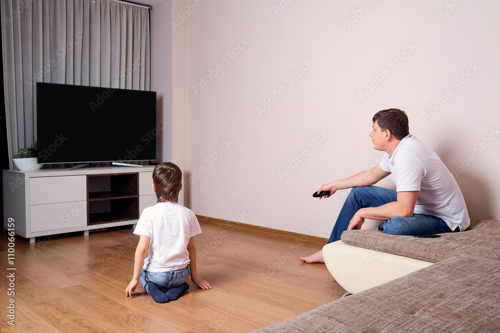 Father and son watching television together Father and son watching television together