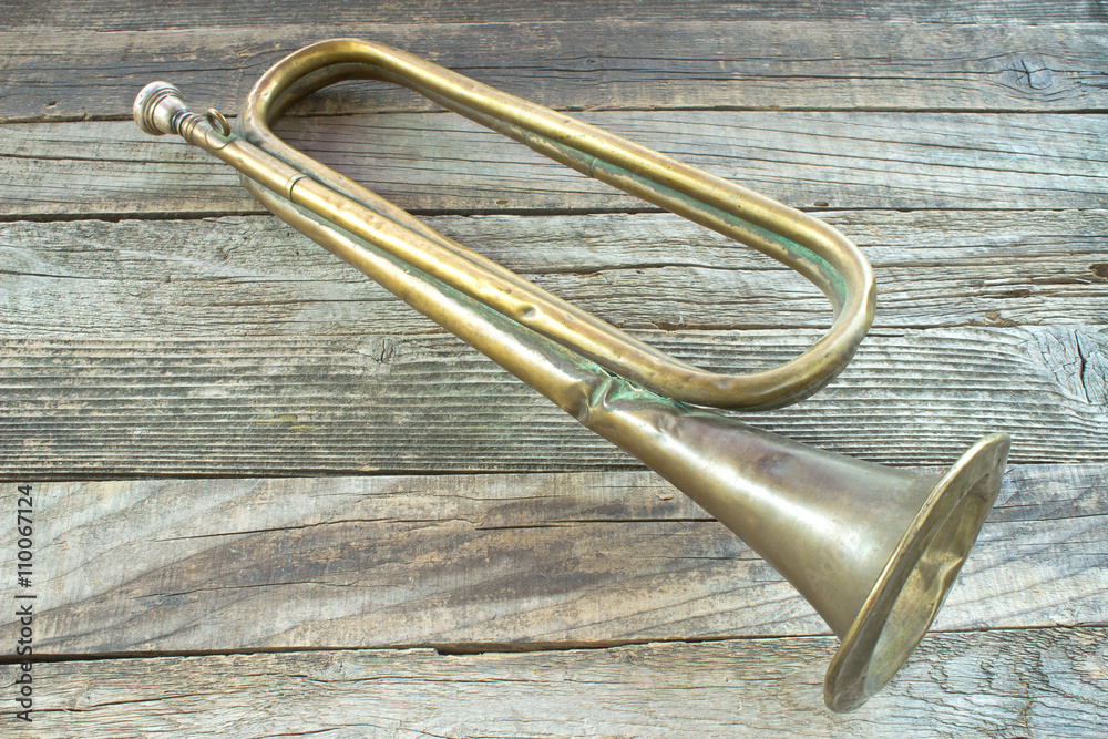 Obraz premium Old broken army trumpet on wooden background