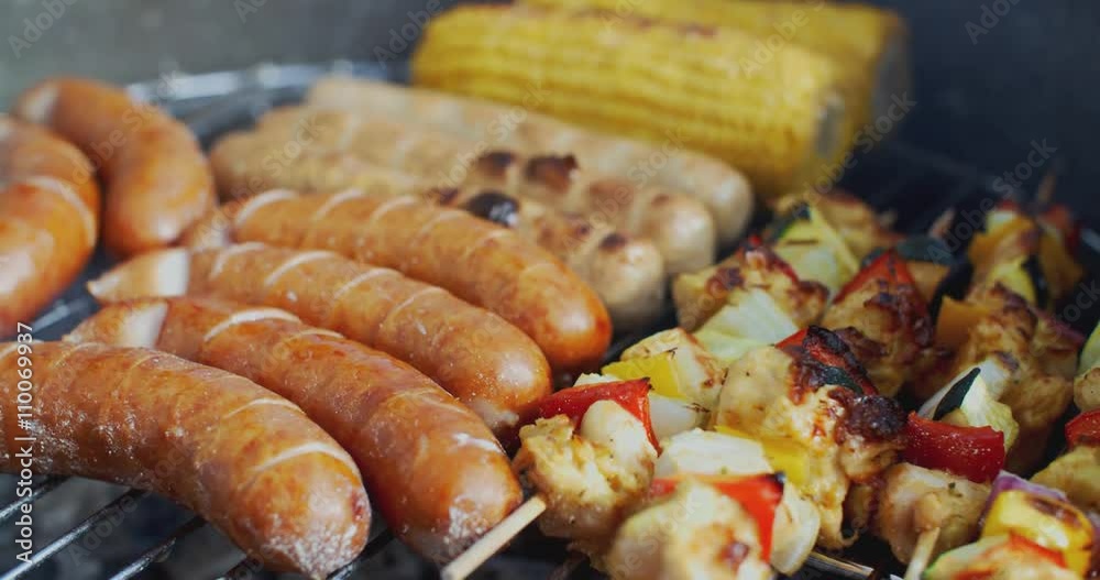Sausages corn and vegetable kebabs grilling together on a summer BBQ or cookout in a close up view Sausages corn and vegetable kebabs grilling together on a summer BBQ or cookout in a close up view