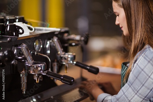 Smiling barista cleaning coffee machine