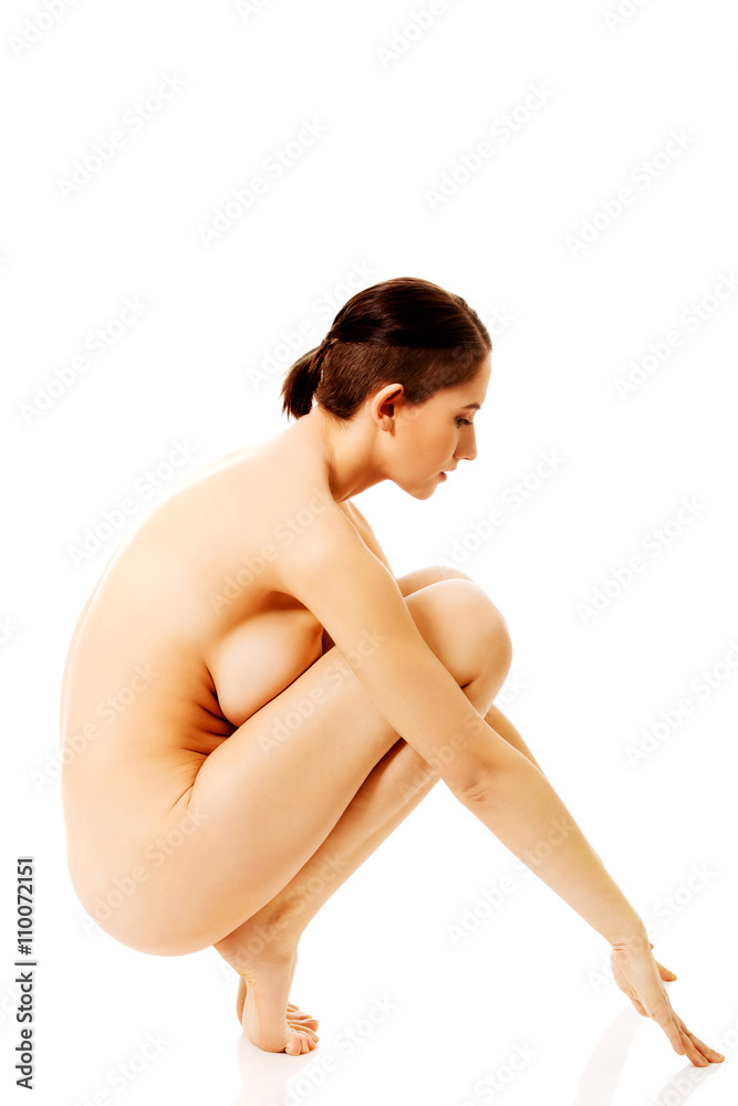 Naklejka premium Side view nude woman squats on the floor