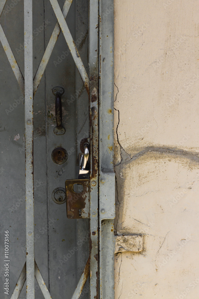 Ausschnitt einer alten verrosteten Gittertür mit Vorhängeschloss