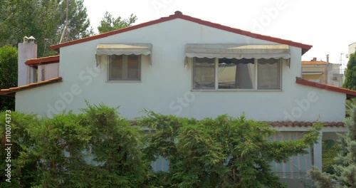 View on house with white wall and red roof. Two windows photo