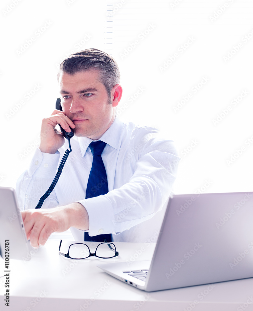 Real estate agent in his office making a phone call, looking for the