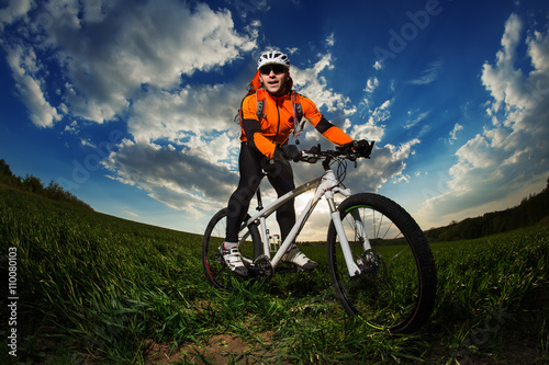 biker in orange jersey riding on green summer field