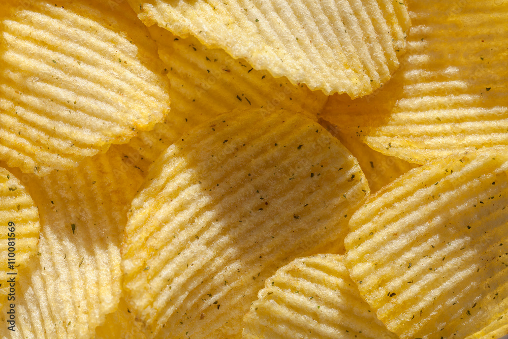 Background of ridged potato chips with spices. Closeup