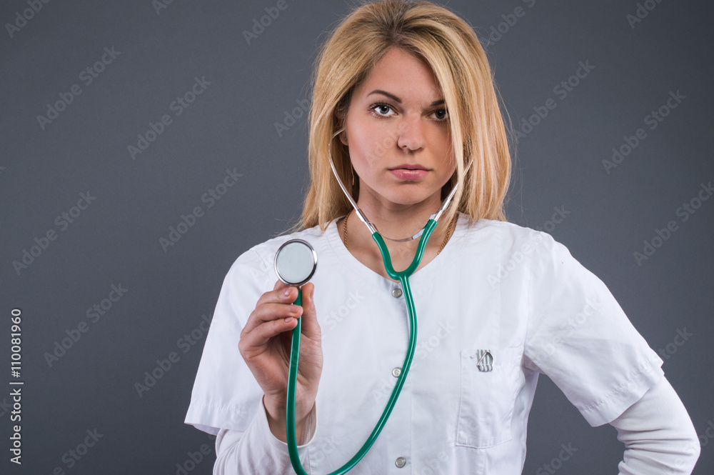 Pretty blonde girl nurse in a white coat with a stethoscope in his hand. Medical concept. Pretty blonde girl nurse in a white coat with a stethoscope in his hand. Medical concept.