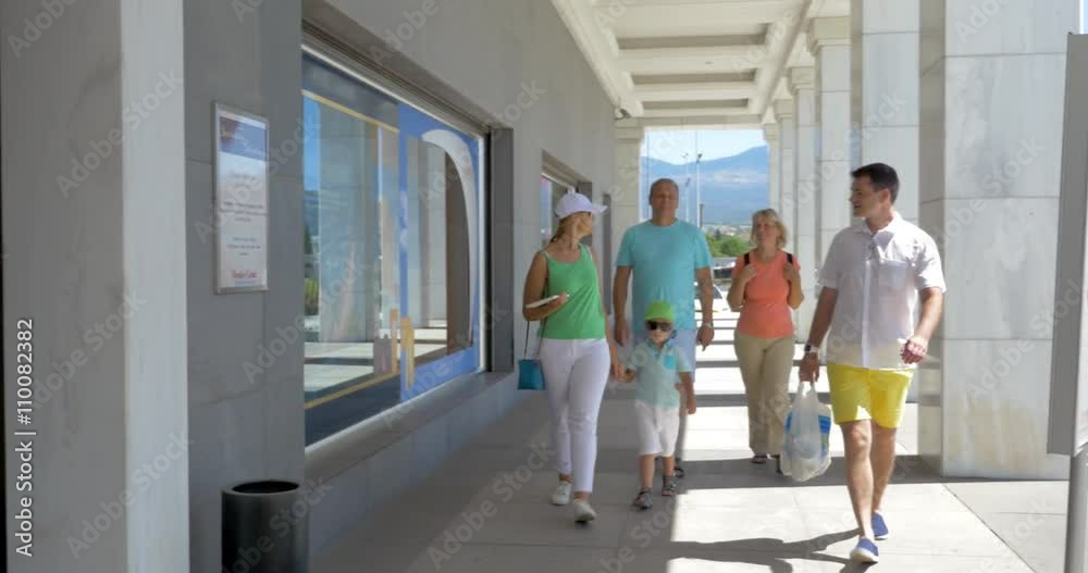 Parents with son and grandparents walking through the automatic doors of supermarket. Family going shopping together