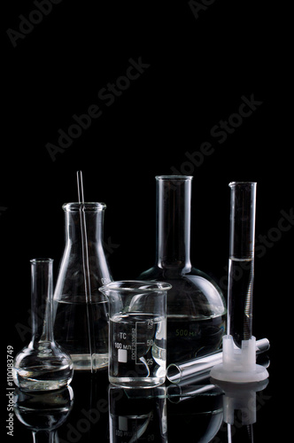 Different laboratory glassware with water to a reflection on a black background