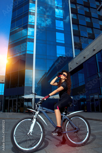 brunette sports woman in sunglasses posing on bicycle
