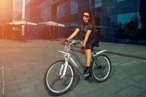 cute brunette sports woman in sunglasses on a bicycle