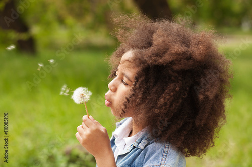 Lovely girl blowing on a dandelion