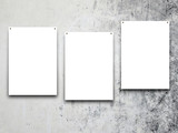 Close-up of three nailed blank frames on grey concrete wall background