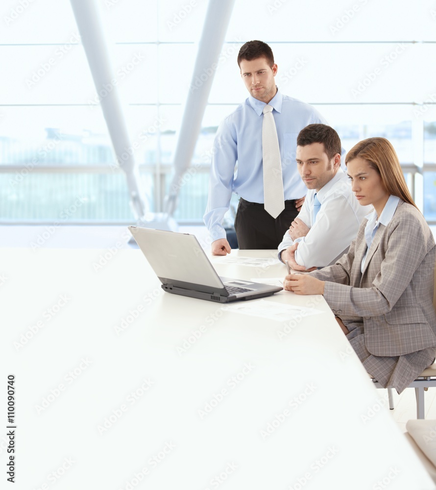 Business team looking at laptop computer screen Business team looking at laptop computer screen