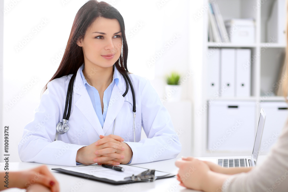 Brunette female doctor talking to patient in the hospital Brunette female doctor talking to patient in the hospital