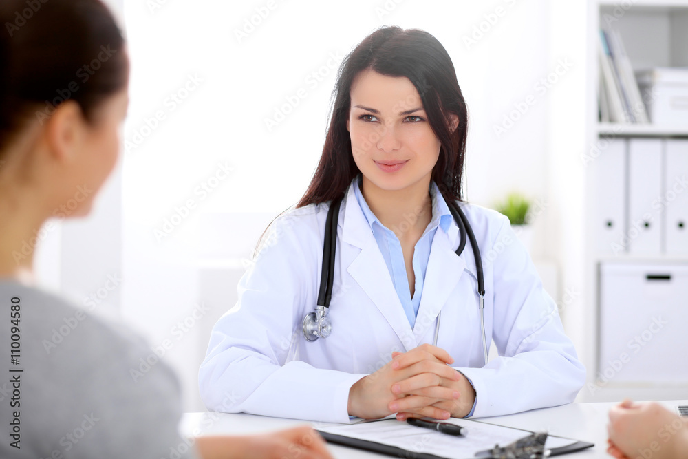 Brunette female doctor talking to patient in the hospital Brunette female doctor talking to patient in the hospital