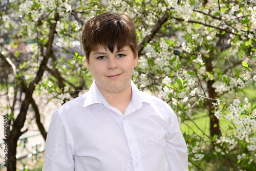 Portrait of a boy teenager on a background of flowering cherries