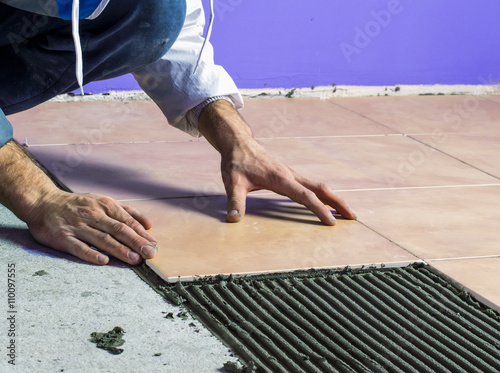 The worker spends construction work, laying tiles on the floor