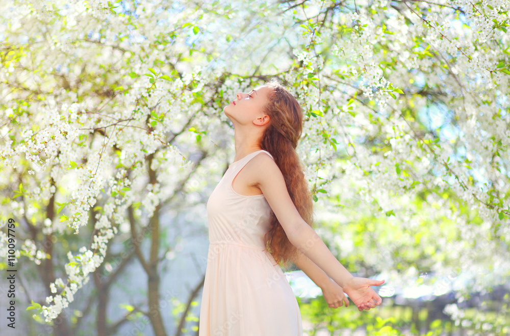 Beautiful young woman enjoying smell in flowering spring garden Beautiful young woman enjoying smell in flowering spring garden