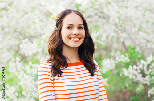 Portrait beautiful smiling young woman in a flowering spring gar