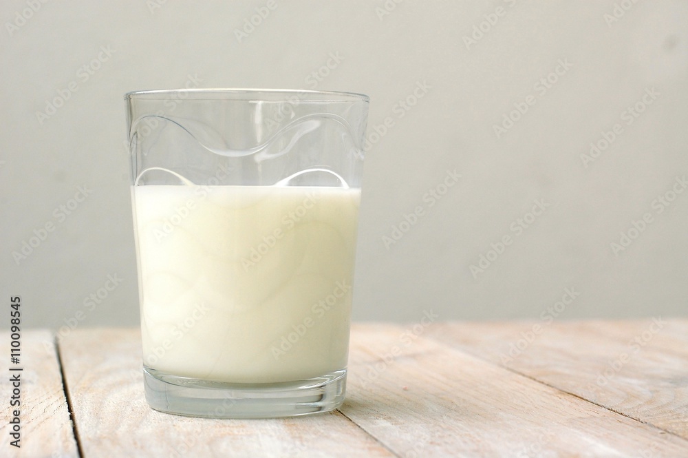 White milk in the glass on the wooden background