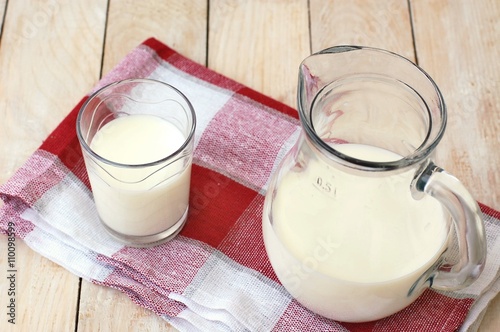 White milk in the glass with the jug on the wooden background