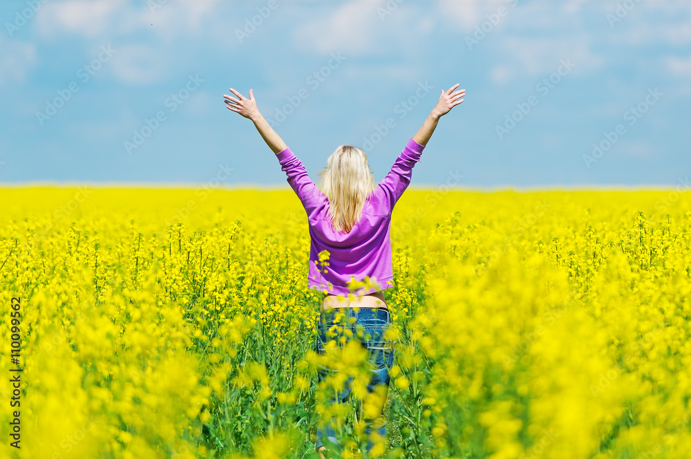 The young blonde in jeans walks on the rape field. The young blonde in jeans walks on the rape field.