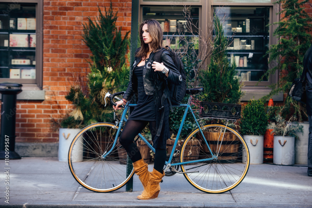Obraz premium Fashionable woman with a bicycle in the city wearing traveler backpack