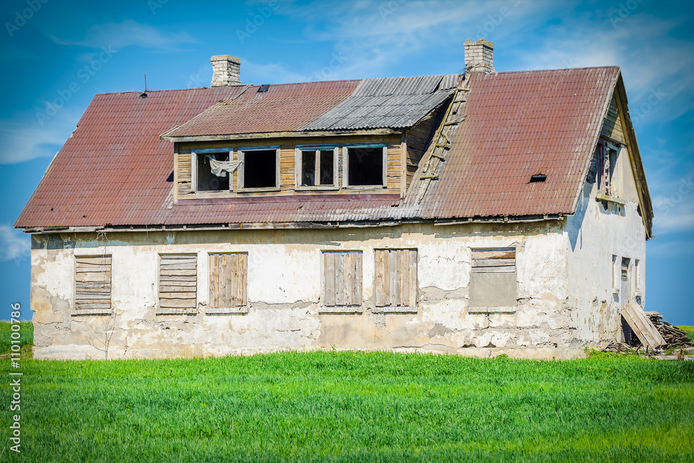 Old abandoned damaged house on grass field