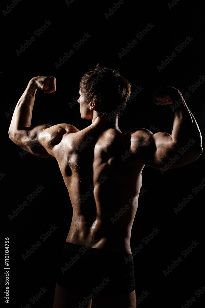 Muscular BACK of male model bodybuilder preparing for fitness training, turned back. Studio shot on black background. Black and white photo. Perfect fitness body. Ideal for commercial. Muscular BACK of male model bodybuilder preparing for fitness training, turned back. Studio shot on black background. Black and white photo. Perfect fitness body. Ideal for commercial.