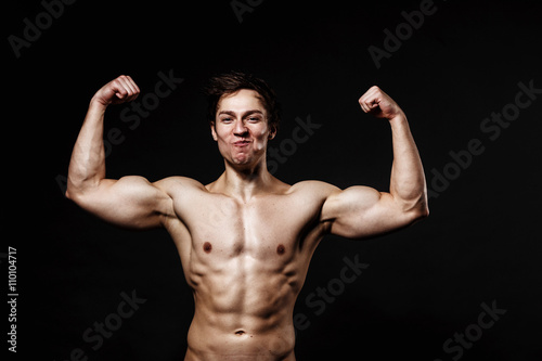 Handsome power athletic man with dumbbell confidently looking forward. Strong bodybuilder with six pack, perfect abs, shoulders, biceps, triceps and chest. Great fitness body. Ideal for commercial  © Maksim Denisenko