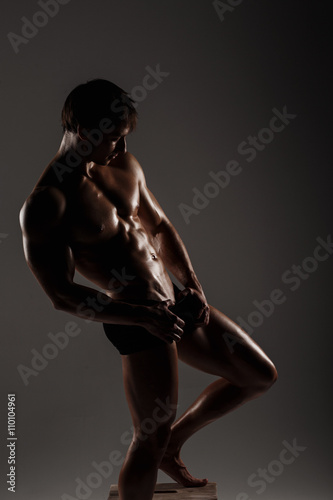 Muscular male model bodybuilder before training. Studio shot on gray background. Fitness MODEL. Great for commercial. Men potency and erection concept