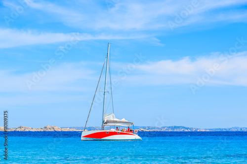 A catamaran sailing on blue sea along a coast of Corsica island, France