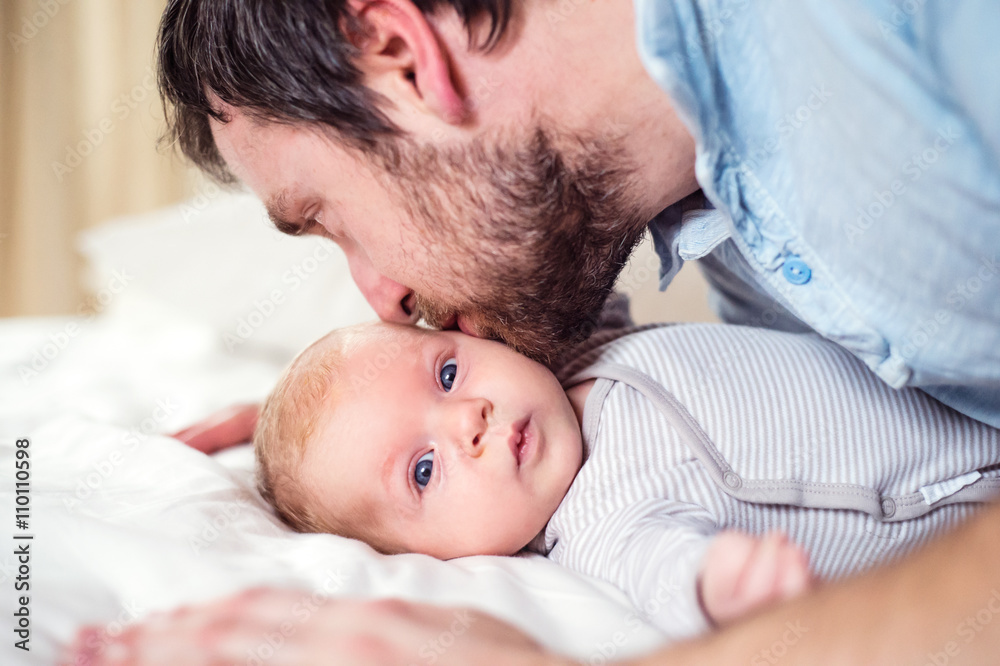 Baby boy lying on bed, held by his father Baby boy lying on bed, held by his father