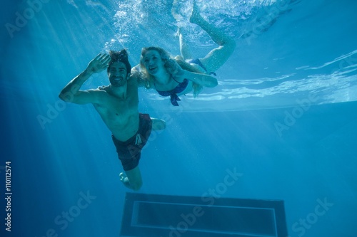 Cute couple swimming underwater in the swimming pool 