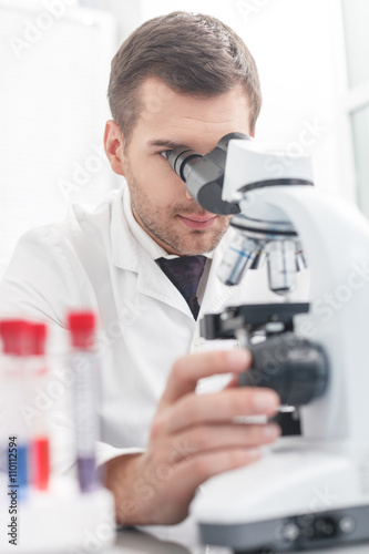 Skillful young scientist is analyzing sample in lab