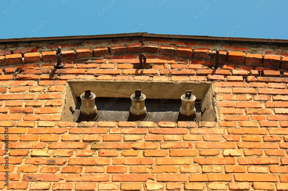 Three powerline insulators in the brick wall of old electrical substation