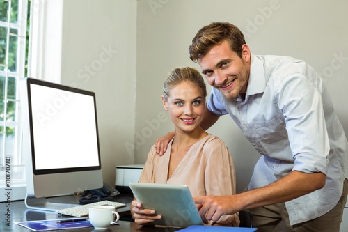 Portrait of happy colleagues using digital tablet at office