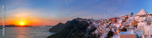 Picturesque panorama of Fira, main town of the island Santorini, sea, white houses and church at sunset, Greece © Kavalenkava
