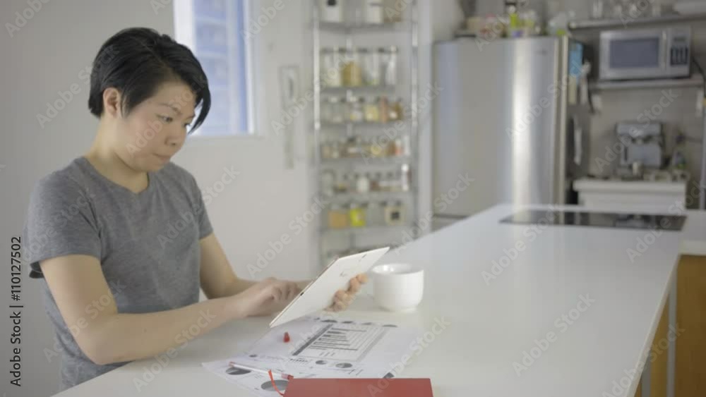 asian woman 4k woking with her tablet in her kitchen at home asian woman 4k woking with her tablet in her kitchen at home